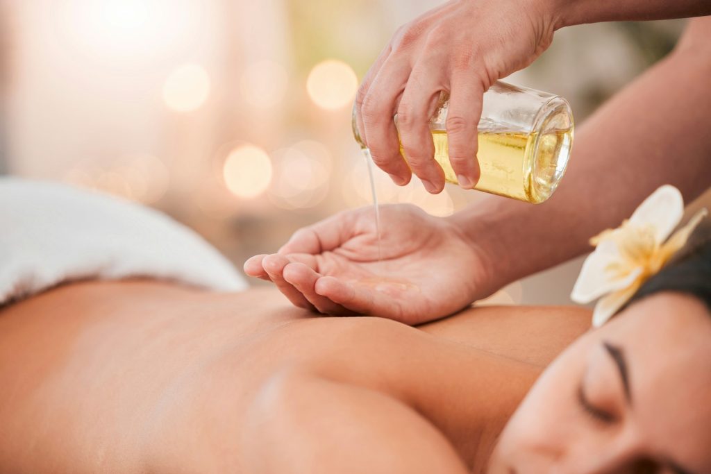 Hand, oil and massage on woman at a spa for wellness, relax and stress relief with back massage and